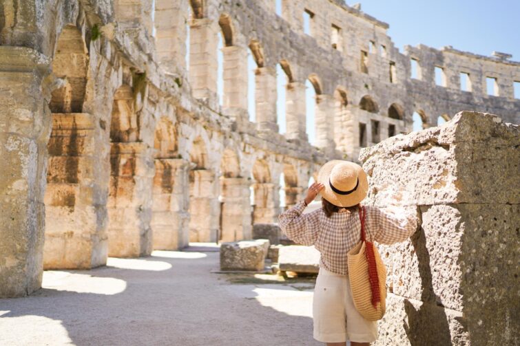 Femme en chapeau contemplant le Colisée à Rome en basse saison pour un voyage écologique
