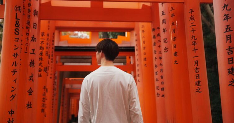 Homme devant un torii au Japon, symbole de la culture japonaise