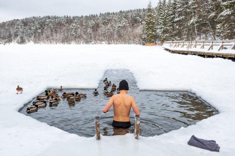 Homme plongeant dans un lac gelé après un sauna, Laponie suédoise