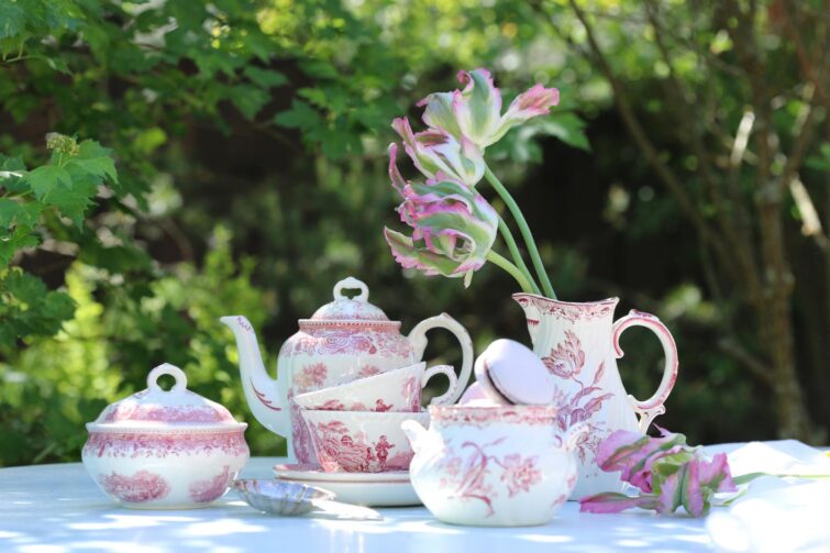 Jardin avec tulipes et ancien pichet en faïence sur une table en bois