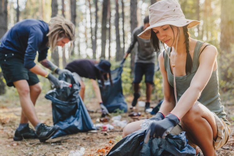 Jeune femme avec un groupe d'activistes nettoyant la forêt pour sensibiliser à la protection de l'environnement