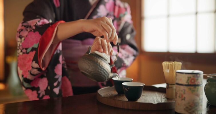 Main de femme japonaise préparant le thé matcha lors d'une cérémonie traditionnelle au Japon