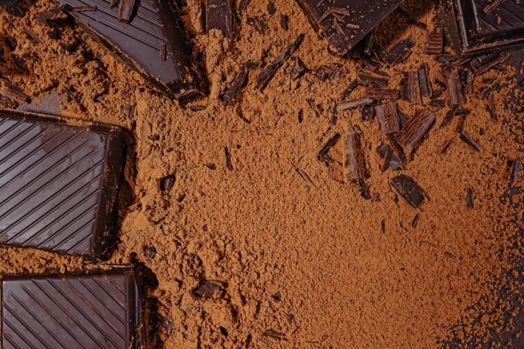 Morceaux et copeaux de chocolat noir amer dispersés sur fond sombre