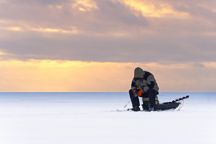 Pêcheur solitaire pratiquant la pêche sur glace en Laponie suédoise