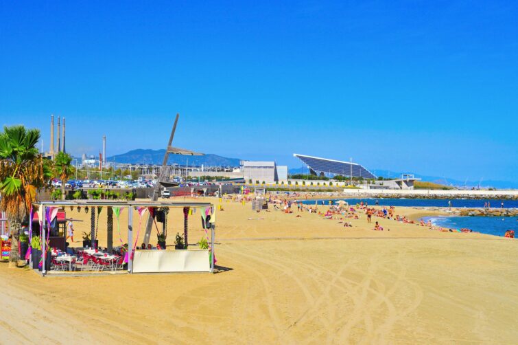 Plage de la Nova Mar Bella à Barcelone, Espagne, avec des parasols colorés et des visiteurs profitant du soleil
