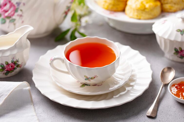 tasse de thé avec scones, confiture et lait sur fond gris, représentant l'élégance britannique