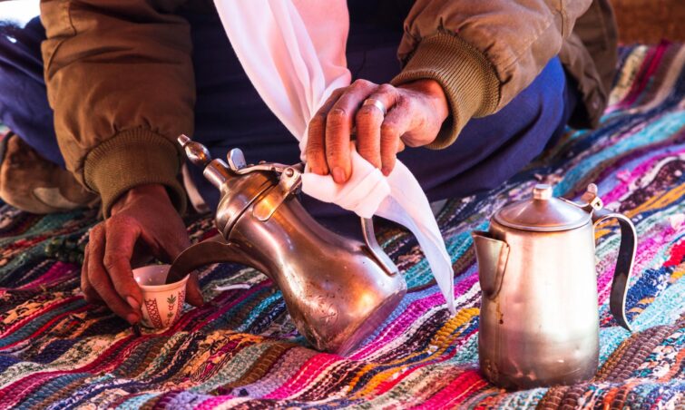 théière et tasse à thé arabe traditionnelle sur un plateau en bois contre un fond désertique