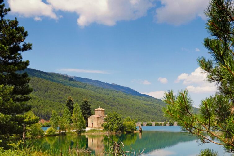 Église Agios Fanourios au bord du lac Doxa en Grèce, paysage paisible avec des reflets sur l'eau