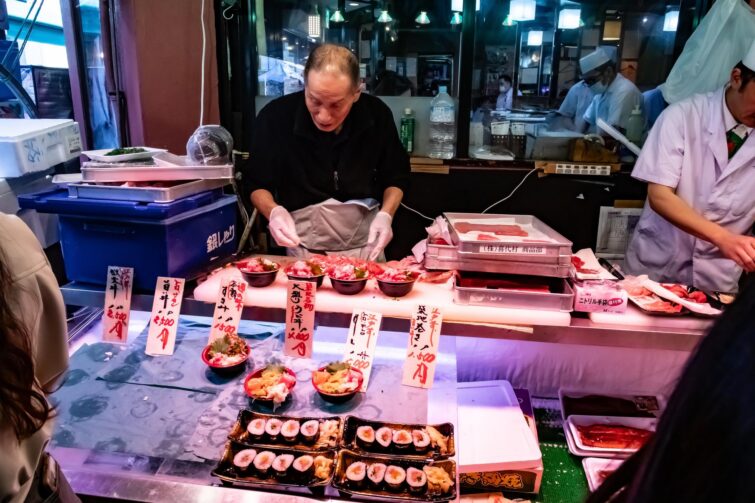 Homme préparant des sushis dans un marché de rue