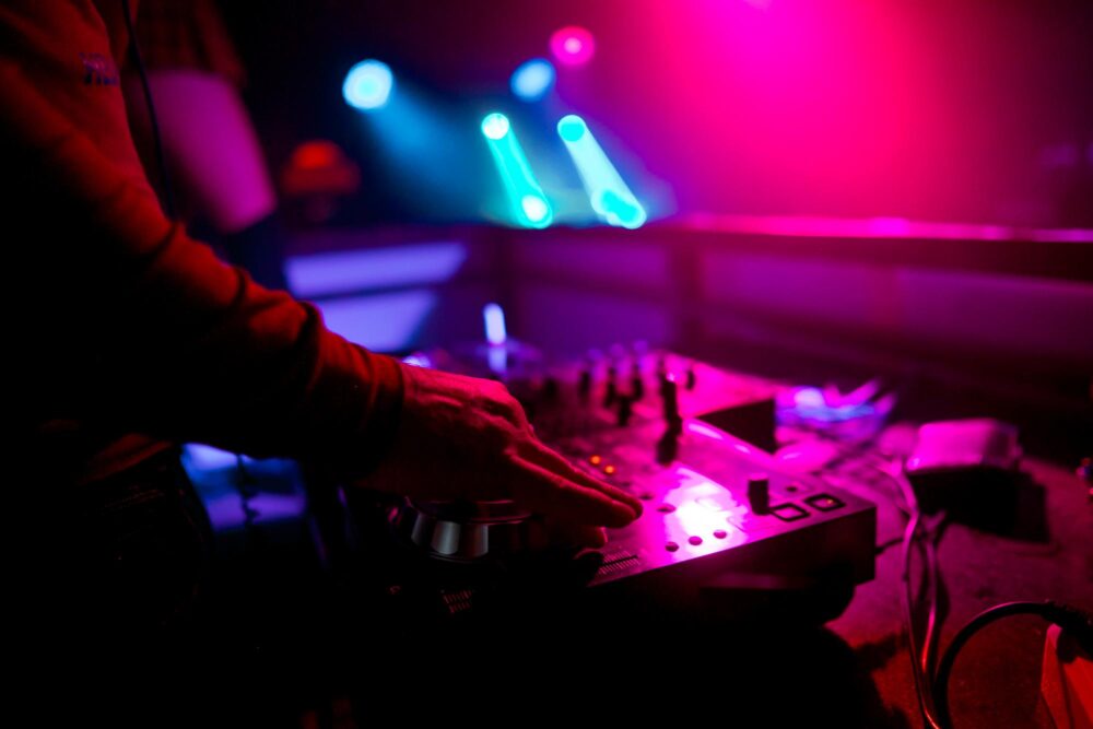 Main d'un DJ qui mixe avec jeux de lumière de fond