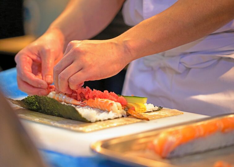 Mains de chef préparant des sushis, cuisine japonaise