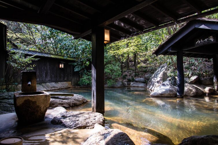 Source chaude japonaise avec des rochers et de la vapeur en montagne