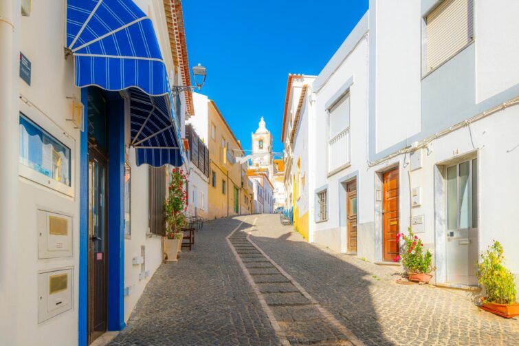 Vue panoramique de la ville de Lagos en Algarve, Portugal, avec un clocher en premier plan et des bâtiments colorés sous un ciel bleu