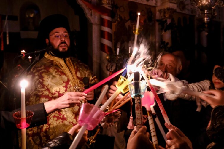 prêtre orthodoxe tenant des bougies lors d'une célébration de Pâques en Grèce