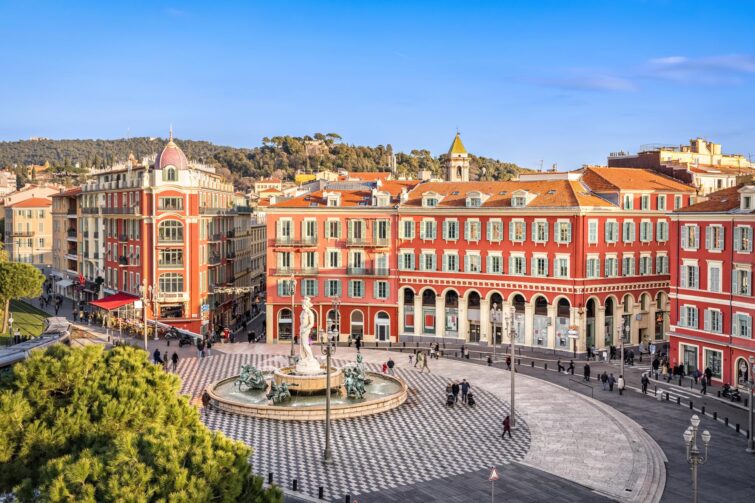 La place Massena avec des bâtiments rouges et une fontaine à Nice