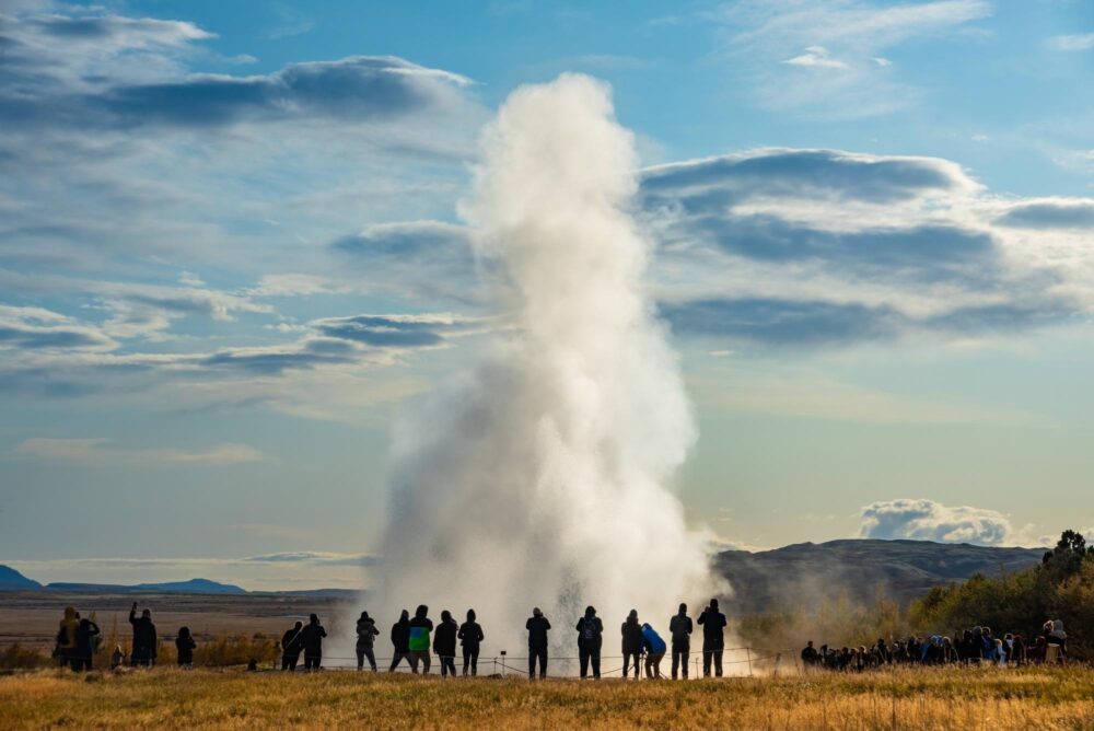 Éruption du geyser Strokkur sous les yeux émerveillés des visiteurs.