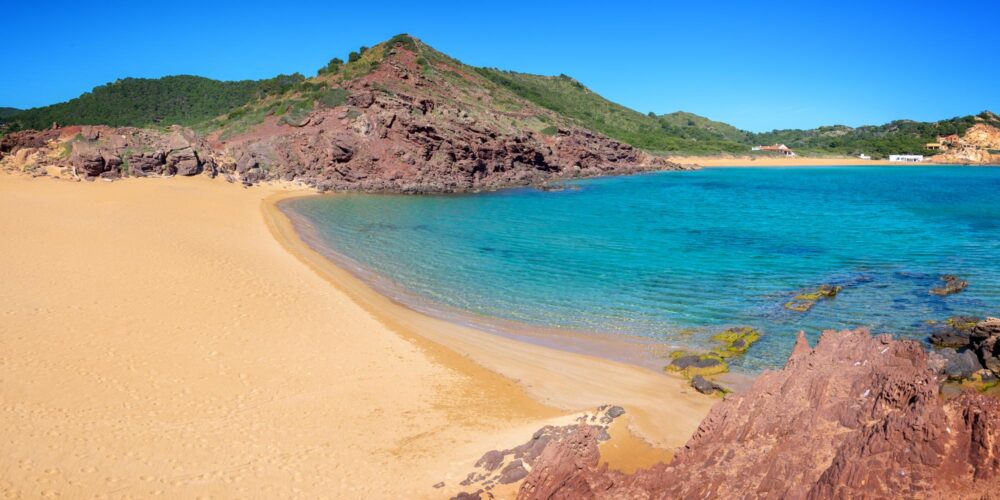 Le sable orangé de la plage Cala Pregonda à Minorque