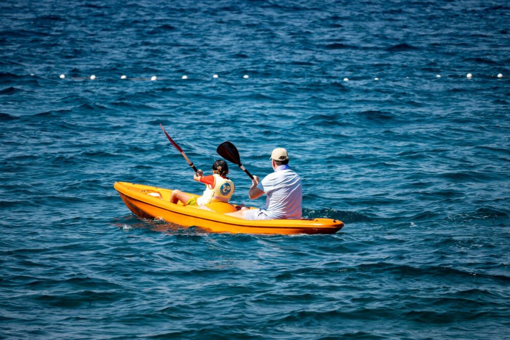 Père et fils ramant en kayak gonflable orange au large de l'île de Brac, Croatie