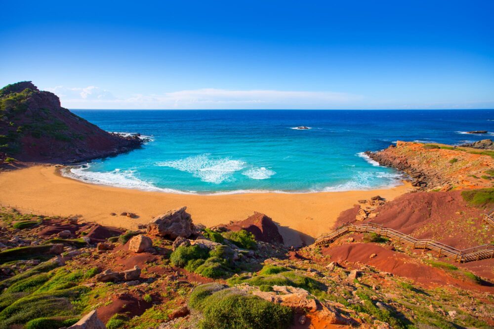 Un beau contraste entre le sable rouge et l'eau bleue de Cala Pilar à Minorque