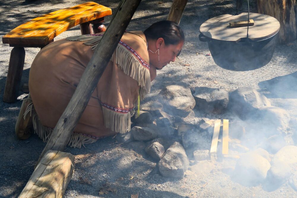 Une femme huron en train d'allumer un feu à Wendake