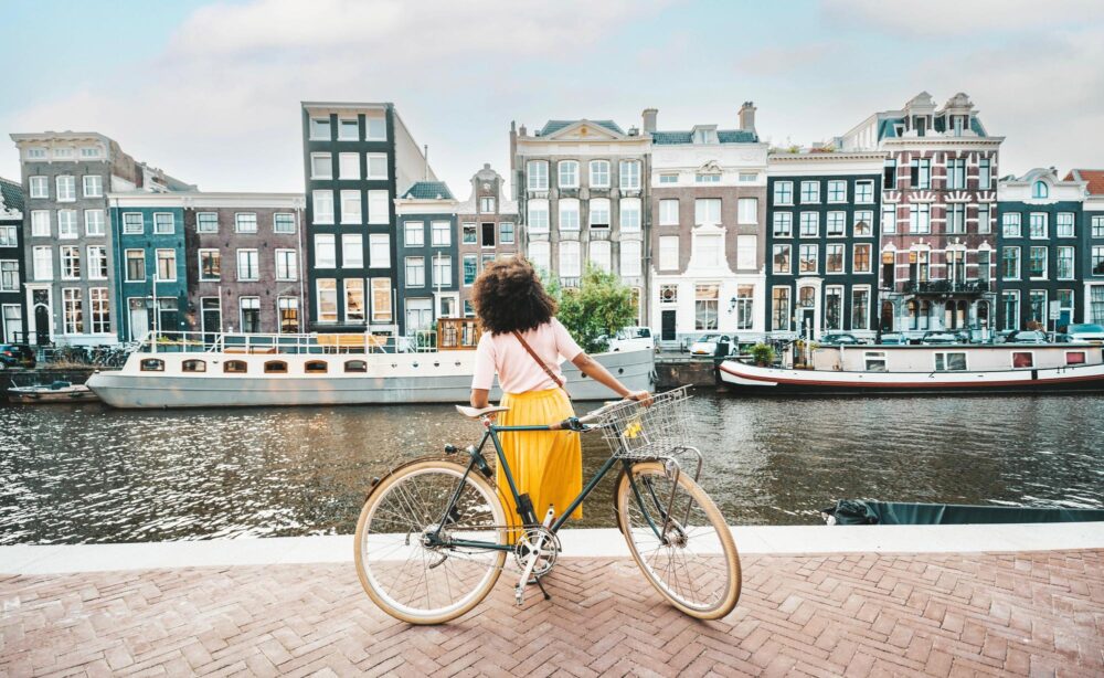 Femme à vélo devant les canaux d'Amsterdam