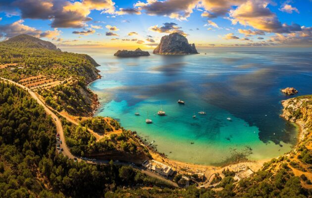 Randonnée à Ibiza, vue sur une plage aux eaux turquoise et le rocher emblématique d'Es Vedrà