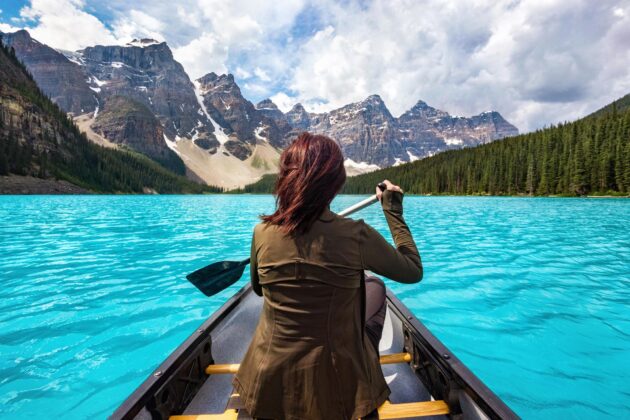 Femme de dos en kayak sur un spot incontournable au Canada, dans le parc national de Banff