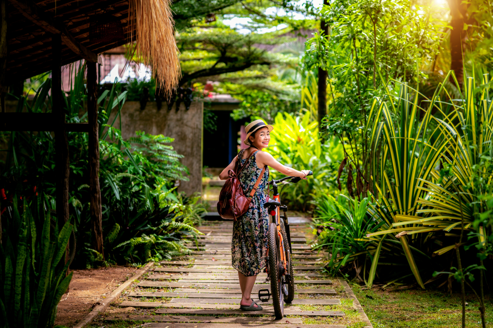 Femme asiatique poussant un vélo sur l'île Koh Mak en Thaïlande