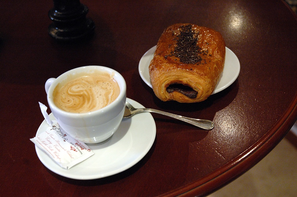 Café servi avec un pain au chocolat dans un bar